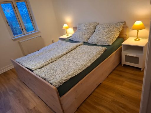 Helle Schlafzimmer mit einem Doppelbett, Nachtisch und warmem Licht.
