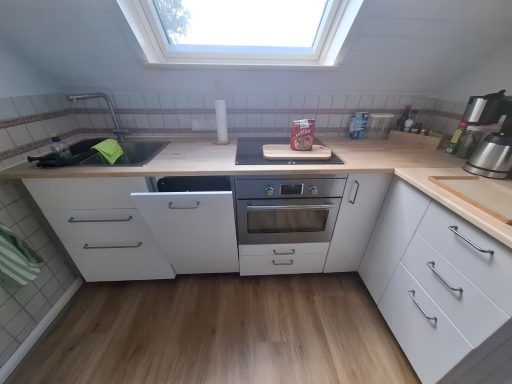 Kleine Küchenzeile mit Herd, Spüle und modernen Küchenunterschränken.