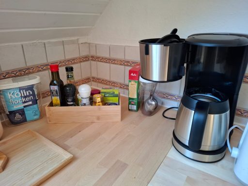 Küchenbereich mit Kaffeemaschine, Gewürzen und einer Holzkiste für Vorräte.